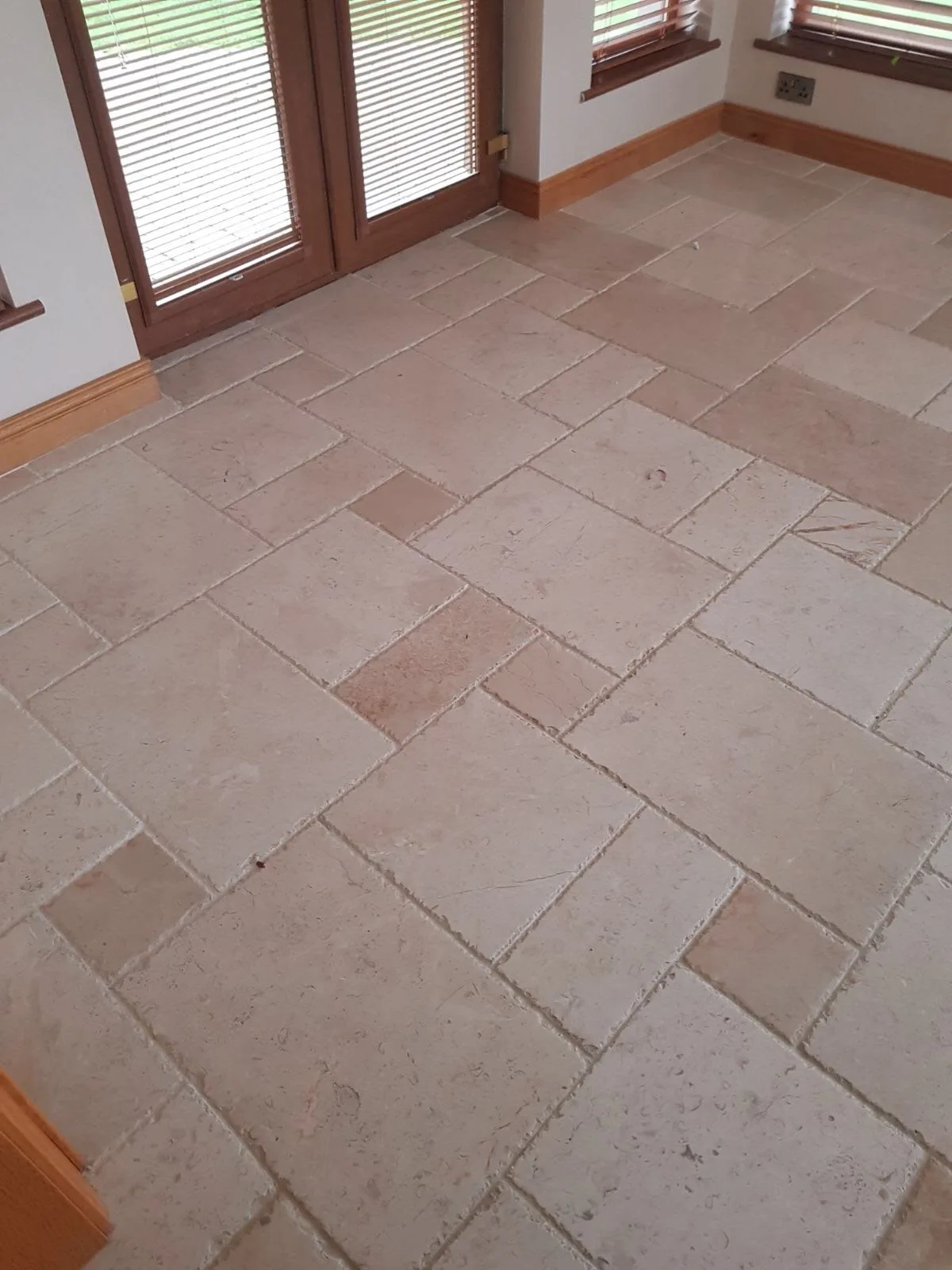 Tumbled limestone living room floor before cleaning, honing and sealing